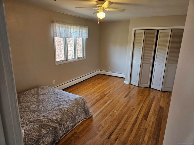 bedroom featuring baseboard heating, wood finished floors, a closet, and ceiling fan