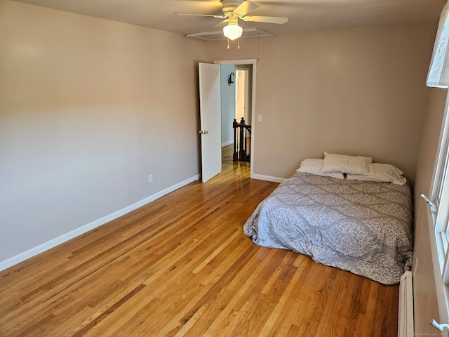 bedroom with light wood-type flooring, ceiling fan, baseboards, and a baseboard radiator