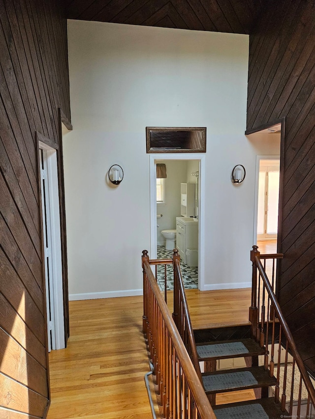 stairway with wood walls, wood finished floors, and baseboards
