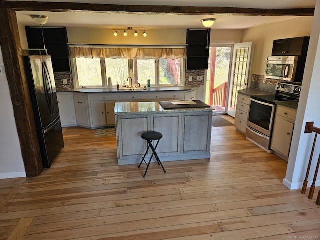 kitchen with tasteful backsplash, light wood finished floors, stainless steel appliances, and a sink
