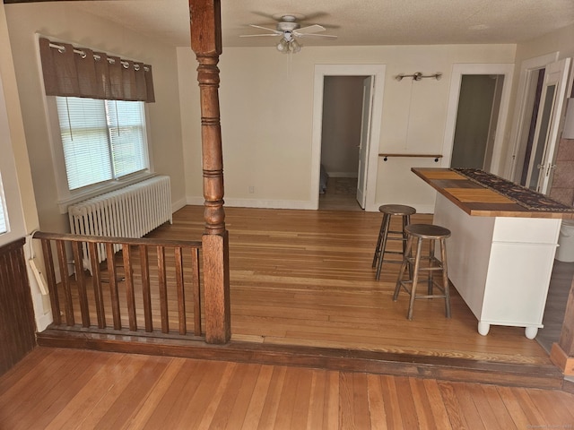 interior space with hardwood / wood-style floors, a ceiling fan, baseboards, and radiator