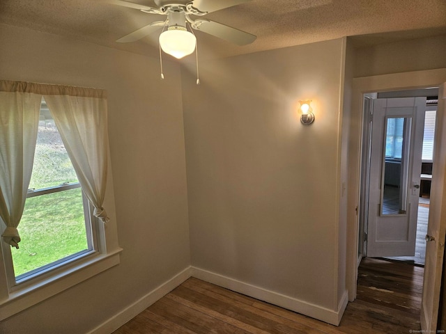 unfurnished room featuring plenty of natural light, wood finished floors, baseboards, and ceiling fan