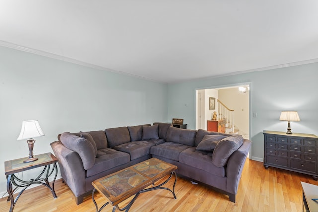 living room featuring light wood-type flooring, crown molding, baseboards, and stairs