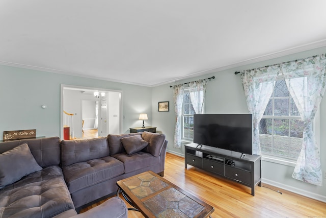 living area with light wood-type flooring, baseboards, and ornamental molding