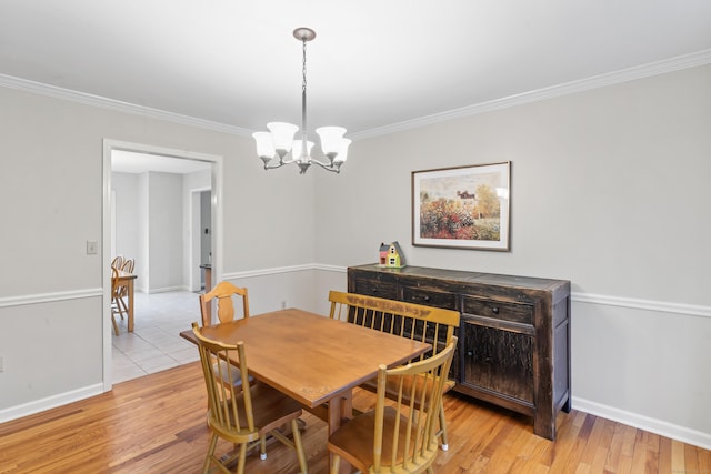 dining area with light wood-style flooring, crown molding, an inviting chandelier, and baseboards