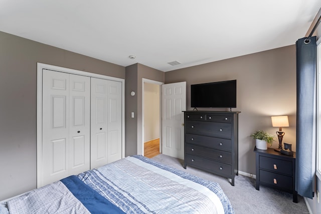 bedroom with a closet, baseboards, light colored carpet, and visible vents