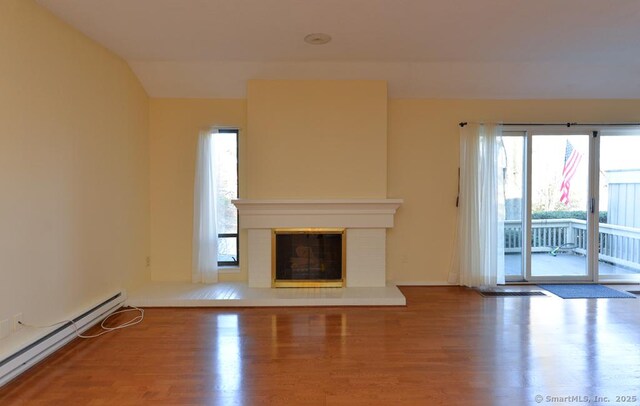 16 Heritage Vlg Unit A, Southbury, CT 06488 - unfurnished living room featuring wood finished floors, a baseboard heating unit, a glass covered fireplace, and lofted ceiling