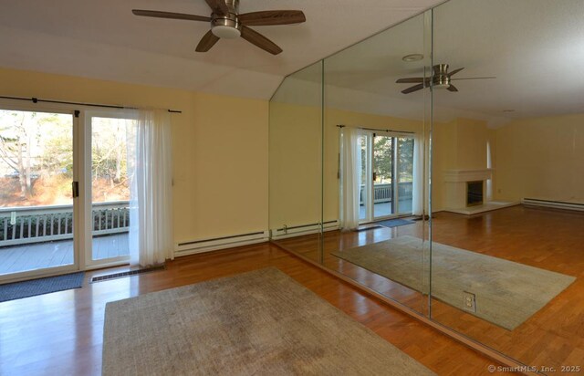 16 Heritage Vlg Unit A, Southbury, CT 06488 - unfurnished living room with a ceiling fan, a baseboard radiator, a fireplace with raised hearth, wood finished floors, and lofted ceiling