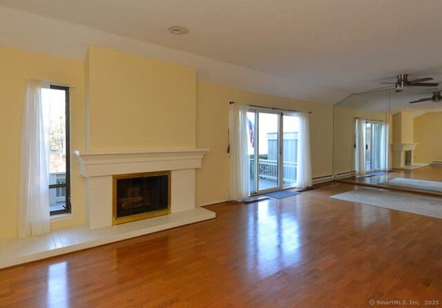 16 Heritage Vlg Unit A, Southbury, CT 06488 - unfurnished living room featuring a glass covered fireplace, ceiling fan, wood finished floors, a baseboard heating unit, and lofted ceiling