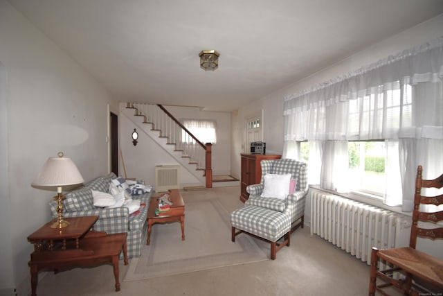 sitting room featuring radiator heating unit, healthy amount of natural light, stairs, and carpet flooring