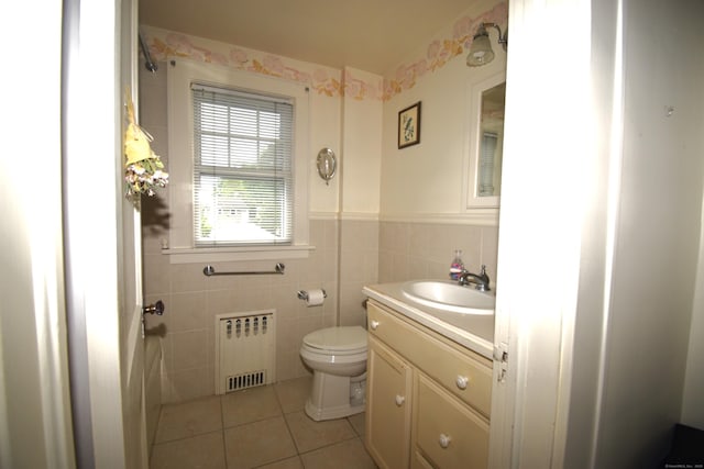 bathroom featuring radiator, tile patterned flooring, toilet, vanity, and wainscoting