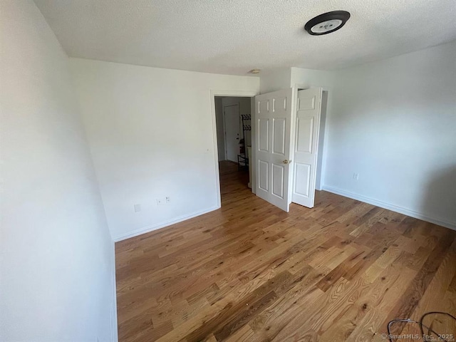 unfurnished bedroom with baseboards, wood finished floors, and a textured ceiling