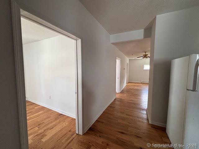 hall with baseboards and wood finished floors