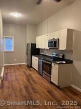kitchen with stainless steel appliances, dark wood-type flooring, baseboards, and dark countertops