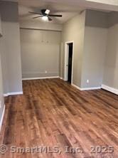 empty room with baseboards, a ceiling fan, and wood finished floors