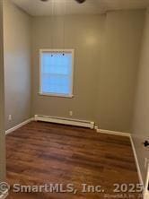 empty room with a baseboard radiator, baseboards, and wood finished floors