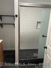 full bathroom with a shower stall, vanity, and tile patterned flooring