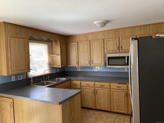 41 Wilshire Blvd, Milford, CT 06460 - kitchen featuring light tile patterned flooring, a peninsula, dark countertops, appliances with stainless steel finishes, and a sink