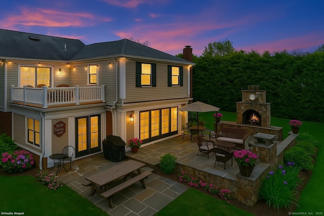 9 Pine Hill Avenue Ext, Norwalk, CT 06855 - back of property at dusk featuring a patio area, a balcony, an outdoor stone fireplace, and a chimney