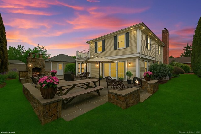 9 Pine Hill Avenue Ext, Norwalk, CT 06855 - back of property at dusk featuring a patio area, an outdoor stone fireplace, a yard, and a balcony