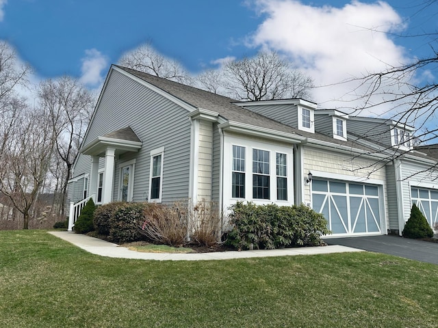 view of home's exterior with a lawn, an attached garage, driveway, and roof with shingles