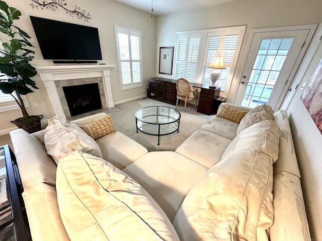 carpeted living room featuring baseboards and a tiled fireplace