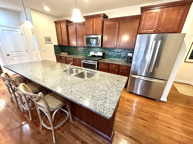 kitchen with decorative backsplash, light wood-style flooring, stainless steel appliances, and a sink