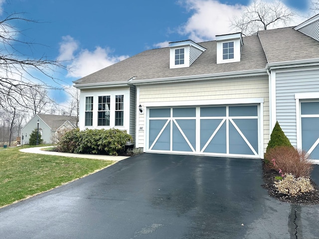 view of front of home with an attached garage, driveway, roof with shingles, and a front yard