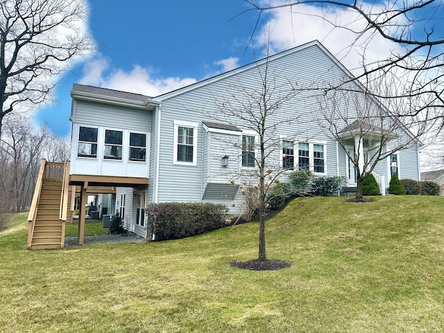 back of property featuring stairway and a yard