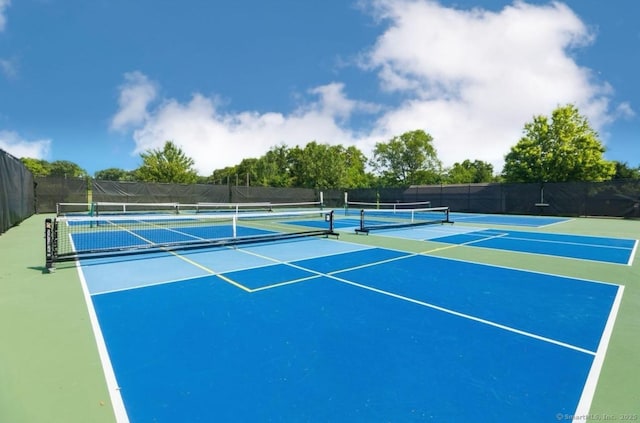 view of tennis court with community basketball court and fence