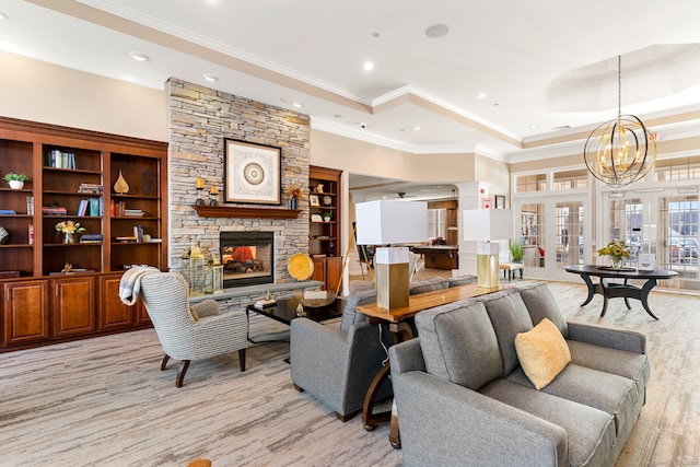 living room featuring light wood-style flooring, a tray ceiling, recessed lighting, a stone fireplace, and ornamental molding
