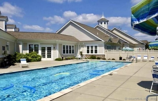 community pool featuring french doors, a patio area, and fence