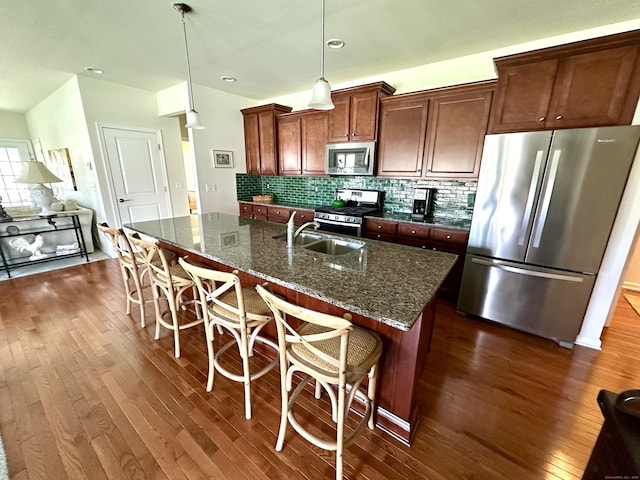 kitchen featuring dark wood-style flooring, stainless steel appliances, a breakfast bar, and a sink