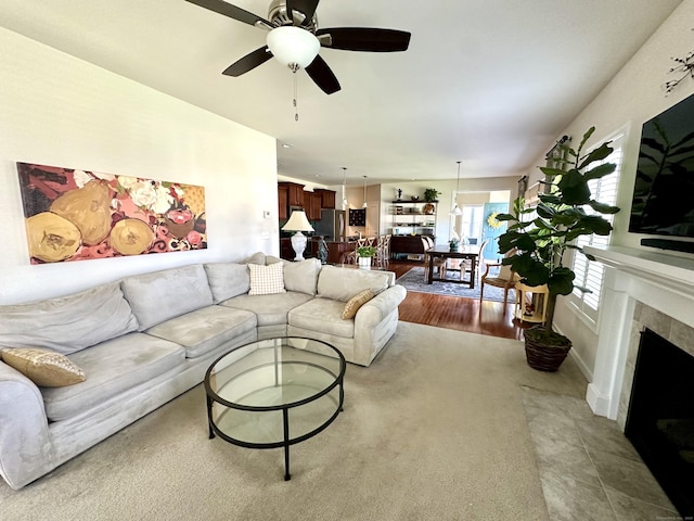living room featuring a tiled fireplace and ceiling fan