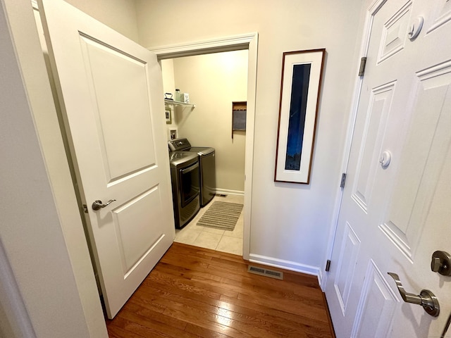 corridor featuring baseboards, hardwood / wood-style flooring, visible vents, and washer and clothes dryer