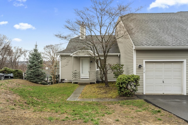 view of front of house featuring aphalt driveway, roof with shingles, a front yard, a chimney, and a garage