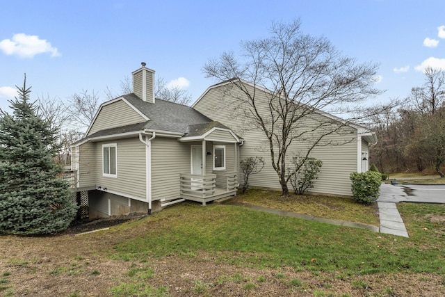 back of house featuring a yard, a shingled roof, and a chimney