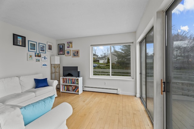 living room featuring a textured ceiling, light wood-type flooring, and baseboard heating