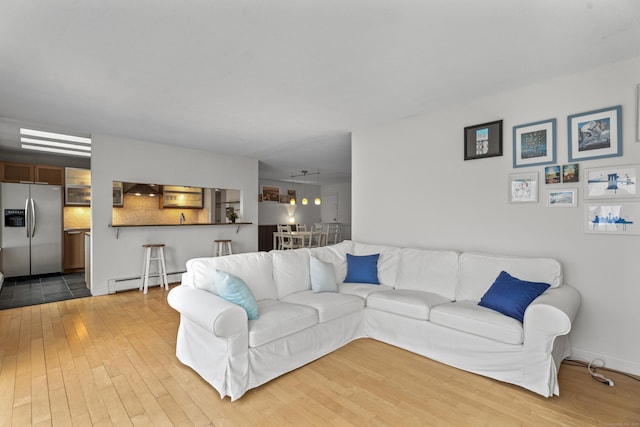 living room featuring a baseboard heating unit and wood finished floors