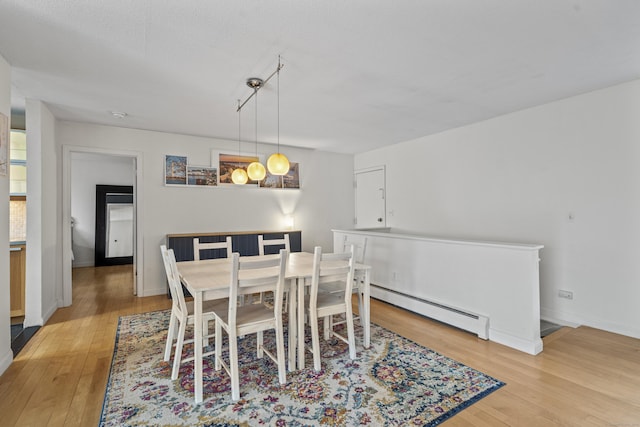 dining room with light wood-type flooring, a baseboard heating unit, and baseboards