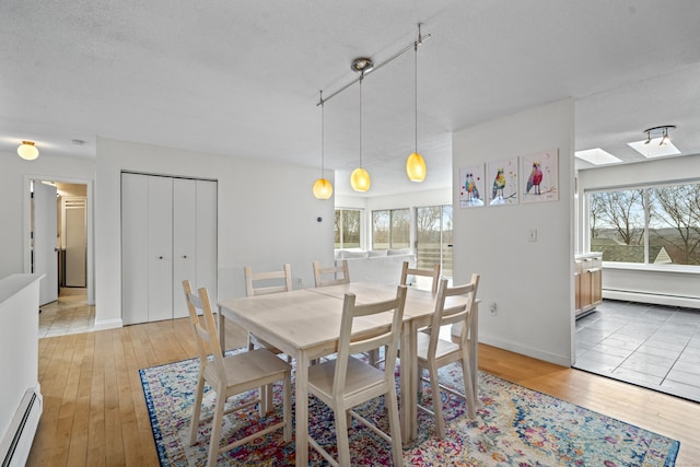 dining area featuring light wood-style flooring, a baseboard heating unit, and a healthy amount of sunlight