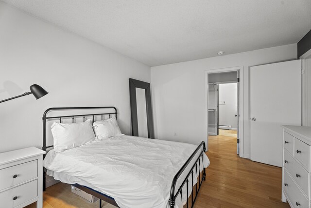 bedroom featuring light wood-style flooring and a baseboard radiator