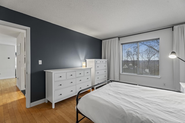 bedroom featuring baseboards, a textured ceiling, and hardwood / wood-style floors