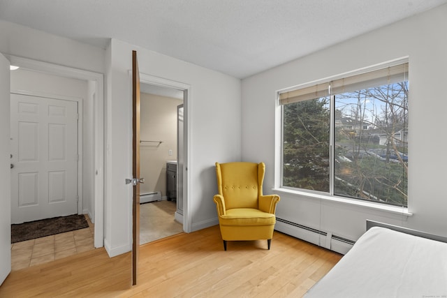 bedroom with a baseboard radiator, a textured ceiling, wood finished floors, and baseboards