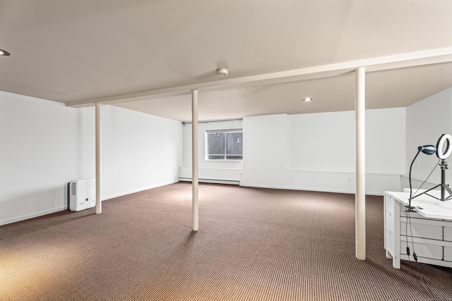 below grade area with a baseboard radiator, carpet, and baseboards