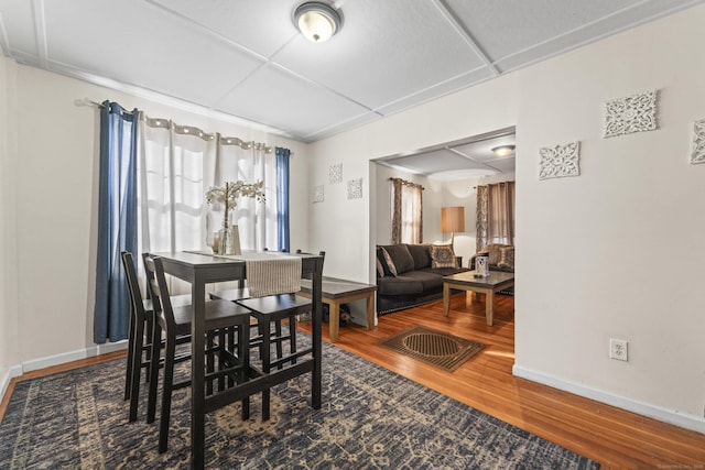 dining space featuring baseboards, wood finished floors, and a drop ceiling