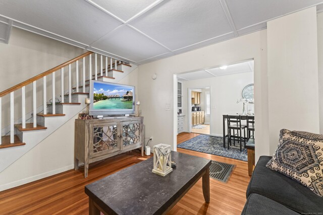 living room featuring baseboards, wood finished floors, and stairway