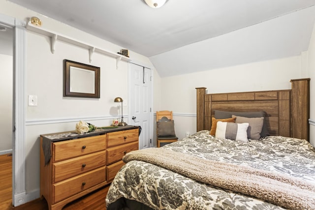 bedroom with dark wood finished floors, baseboards, lofted ceiling, and a closet