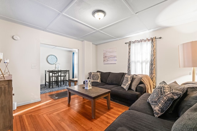 living room with baseboards, wood finished floors, and coffered ceiling