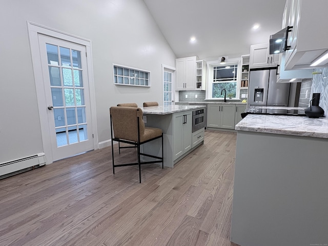 220 W Rd, Colchester, CT 06415 - kitchen with open shelves, decorative backsplash, light wood-style floors, a breakfast bar, and a center island